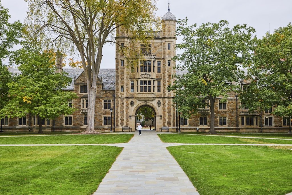 Student walking a pathway through a collegiate campus